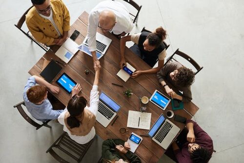 A group of colleagues at the table greets a newly hired colleague