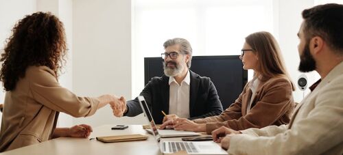 two people shaking hands in a team meeting