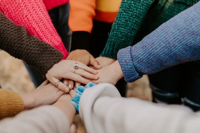 People holding their hands on top of each other as a symbol of teamwork