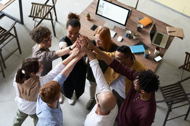 HR team high-fiving after successfully implementing HR strategies for unifying cultures in transition