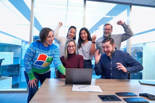 Happy people looking at a laptop and celebrating