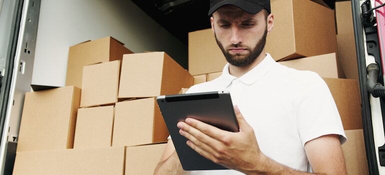 A man writing on a pad with office relocation boxes behind him.