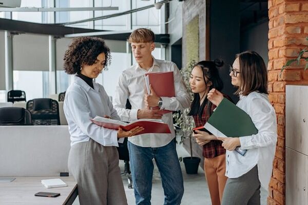 Group of people standing next to a table in an office, holding folders with documents