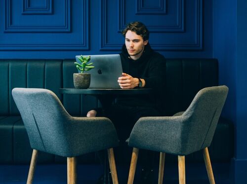 Man sitting on couch with looking at his macbook on table