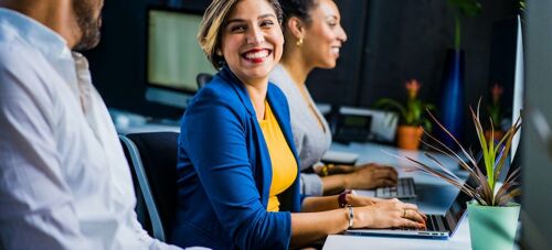 three people working on their laptops and smiling