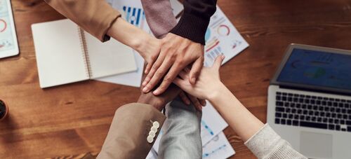 coworkers putting hands together so HR can prepare for the next decade