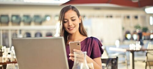 a woman using her phone and laptop