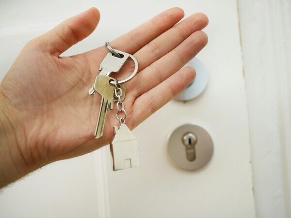 Hand with a set of keys in front a door