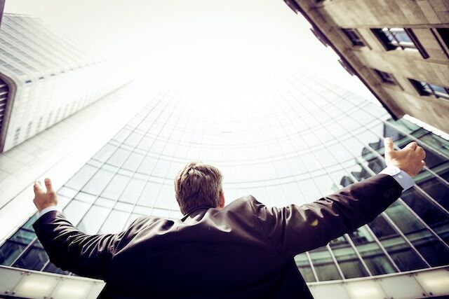 Businessman looking up toward the sky while standing next to a commercial building