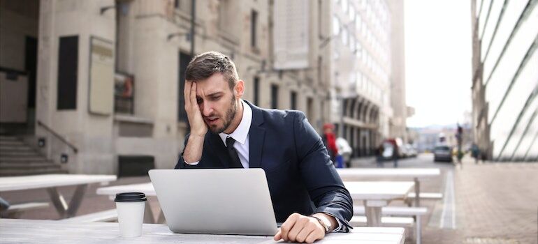 a man looking at a laptop and holding his head