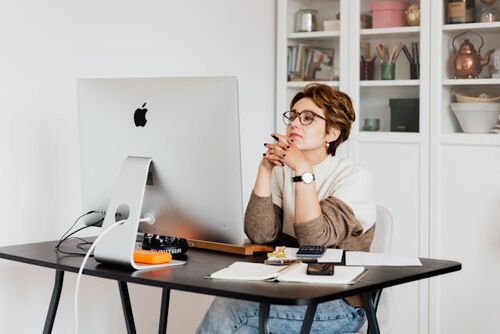 A woman sitting at her desk looking at a computer monitor